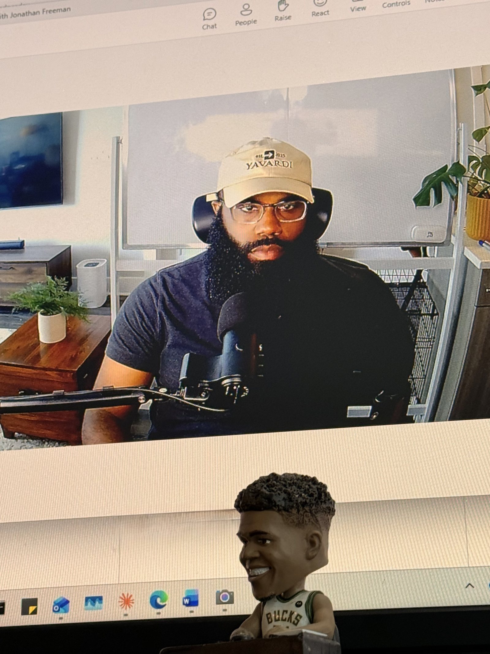 Jonathan Freeman at his desk — mic, monitors, plants and a Bucks bobblehead