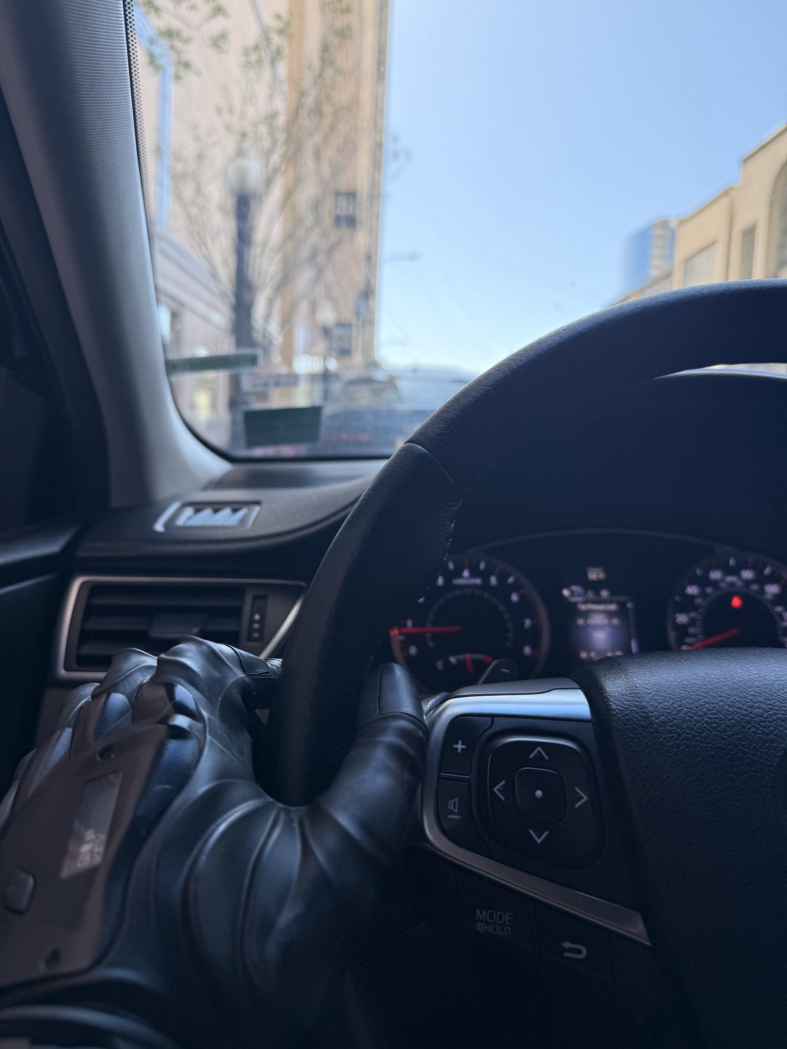 Jonathan Freeman's prosthetic hand resting on a car steering wheel on a downtown street